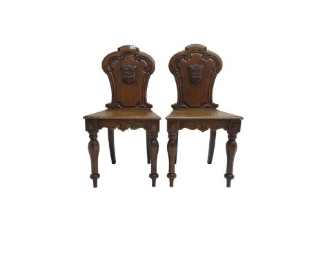 Pair Victorian oak hall chairs, scallop shaped back with carved scrolls and central shield moulding, panel seat over shaped f