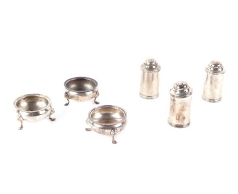 A set of three Edwardian silver pepperettes with blue glass liners, London 1909; together with three matching cauldron form s