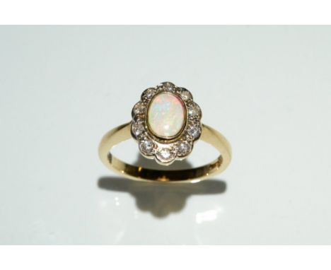 An opal and diamond cluster ring, central oval opal surrounded by a band of ten diamond accents, 9ct gold shank, size N, 3.1g