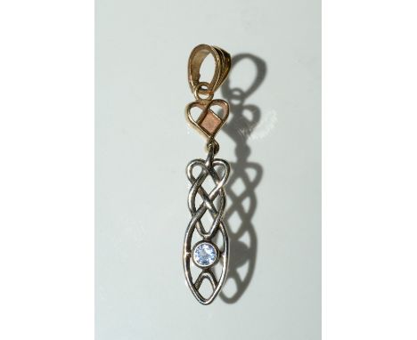 A yellow and white metal Celtic drop pendant, inset with a single pale blue round cut topaz, tests as 9ct gold, indistinctly 