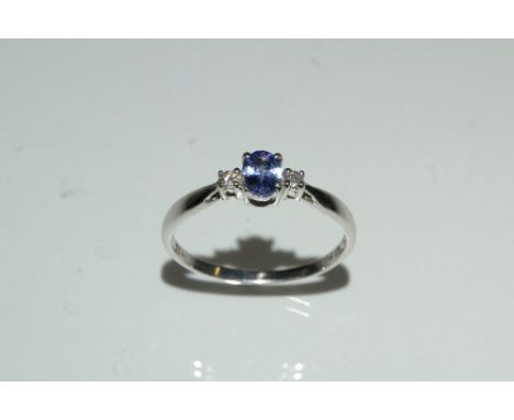 A tanzanite and diamond trilogy ring, central oval tanzanite flanked by a diamond accent to either side, 9ct gold shank, stam