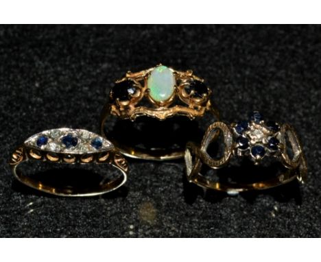 An opal and sapphire ring, central oval white opal doublet flanked by an oval deep blue sapphire to each side, open crest set