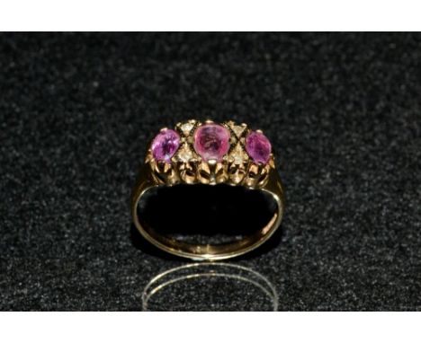 A pink spinel and diamond seven stone ring, set with three oval graduated pink spinels, each divided by a pair of round cut d