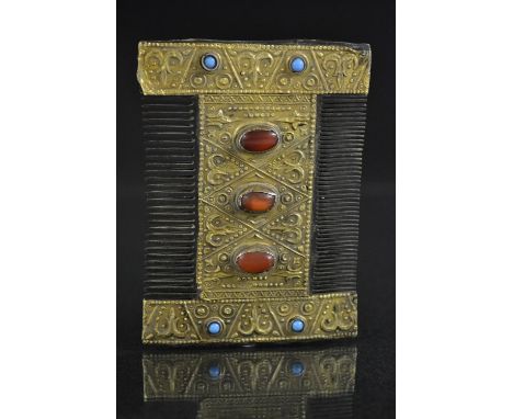 Antiquities - a gilt metal bound hand cut wooden comb, rectangular two sided comb encased within an embossed and jeweled fram