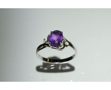 An amethyst and diamond trilogy ring, central oval amethyst quarter claw set above diamond accented shoulders, 14 ct white go