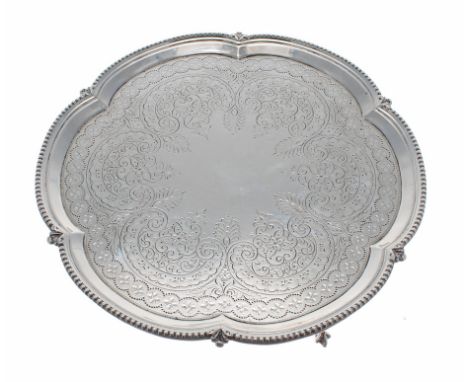 George V cast silver salver of lobed form with reeded edge border, foliate engraved decoration to the centre, raised on three