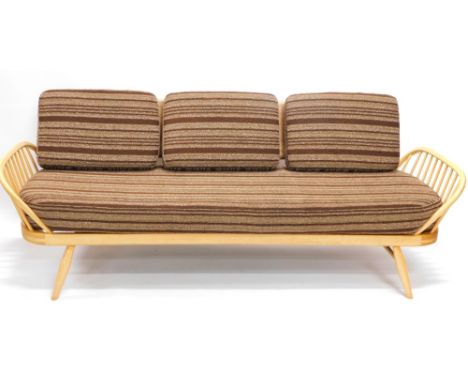 An Ercol beech day bed, with a shaped back and loose cushions to the back and seat on turned tapering legs, 208cm wide.