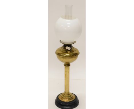 An early 20thC brass oil lamp, with clear chimney, milk glass shade and brass stem, on ebonised foot, 80cm high.