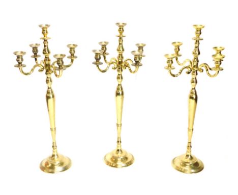 A set of three brass five branch candelabra, each on a domed foot, 99cm high.