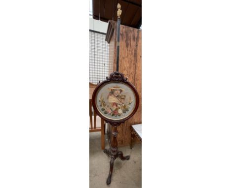 A Victorian mahogany pole screen, with a figural terminal, the circular screen with a needlework panel depicting a maiden on 