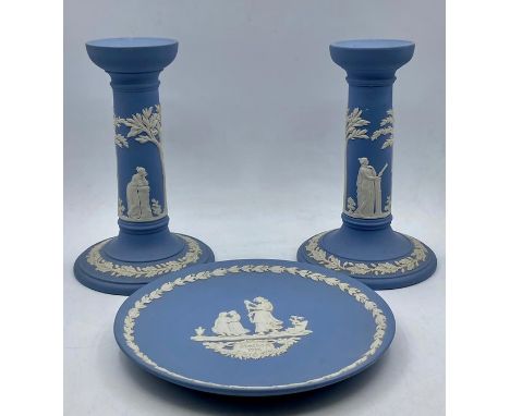A group of vintage wedgwood ‘light blue’ jasper ware comprising of a pair of candlesticks and a plate, (17 cm tall). (3)