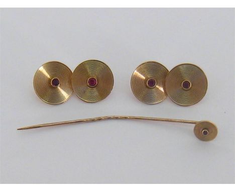 A set of 9 carat gold and synthetic ruby cuff links, the engine turned discs 14mm diameter, with a round cut stone to the cen