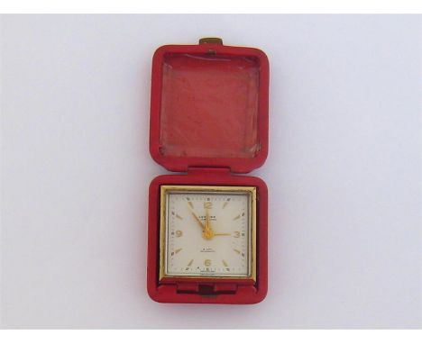 Looting, a mid 20th century travelling 8-day alarm clock, the gilt metal square case 4.7cm, in a red leather travelling case
