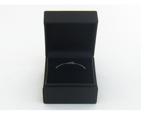 An 18 carat white gold bangle by Lily Gabriella, with Celtic knot motif, stamped ‘750’, 4.3gms, in its original box
