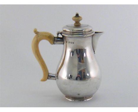 A silver hot water jug by Sebastian Garrard, London, 1932, baluster form on collet foot, ivory handle and finial, 17.5 cm. hi