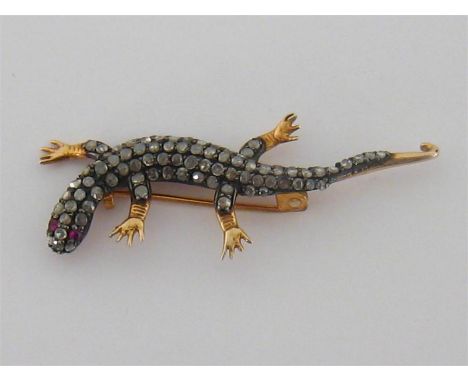 A diamond and ruby lizard brooch, set along its body with rose cut diamonds, with ruby set eyes, mounted in gold and silver, 