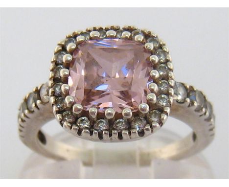 A silver and pink stone ring, the central princess cut stone in a white stone surround, extending down to the shoulders, fing
