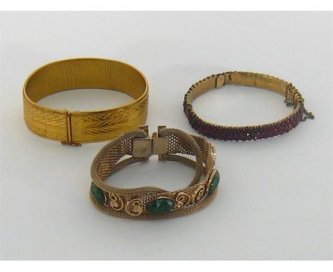 A late 19th century silver gilt and red paste bangle, composed of three rows of uniform stones, together with two yellow meta