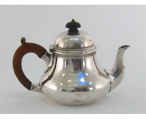 A silver teapot by Sebastian Garrard, London, 1919, squat baluster form, scalloped faceted spout, wood handle and ebonised fi
