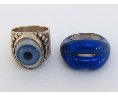 Two silver rings, the first set to the centre with a realistically modelled glass eye, finger size M; the second designed as 