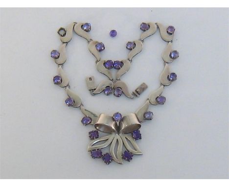 A South American silver and amethyst necklace, centred on a bow motif, set along its length with uniform 7.2mm round cut ston
