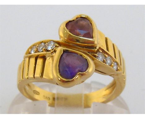 An 18 carat gold, amethyst and diamond ring, the two heart shaped stones obliquely set, with brilliant cut accents between, t