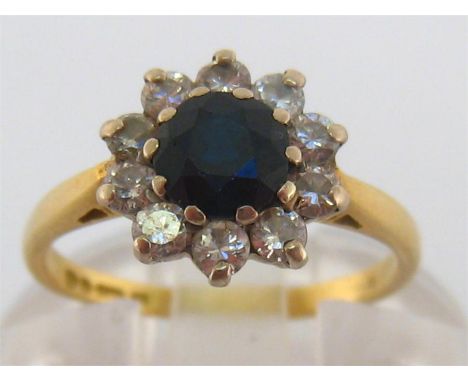 A sapphire and diamond cluster ring, the central round cut stone 5.2mm diameter, in a surround of brilliants, the 18 carat go