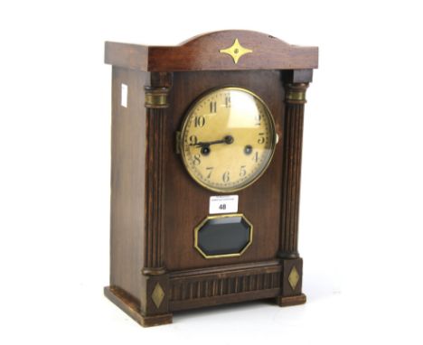 A German eight day chiming mantel clock. The painted dial with Arabic numerals, flanked by columns, in a carved wooden case, 