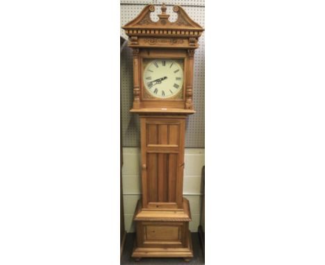 A pine cupboard in the form of a longcase clock. With white painted clock dial and black Roman numerals, within glazed Corint
