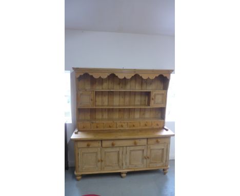 A 19th century and later stripped pine dresser with an open rack top incorporating two small cupboards and seven spice drawer