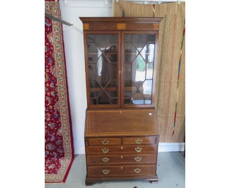An Edwardian bureau bookcase with a two door glazed top over a fitted interior above five oak lined drawers on shaped bracket