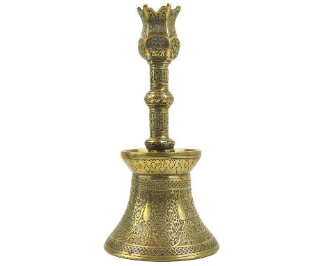 A Persian engraved brass candlestick, Qajar, 19th century.  The tall cylindrical screw in neck with bands of script, above a 