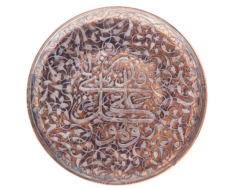 A Mamluk Revival copper and silver inlaid charger, circa 1900.  With a central arabic inscription amonst scrolling leafy tend