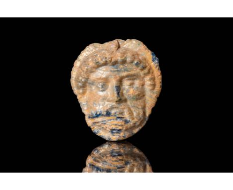 Ca. 330 - 250 BC.
A glass pendant in the shape of a male head, depicting a strong, forward-facing visage with large eyes, a p