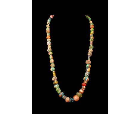 Ca. 600 - 400 BC.
A necklace featuring a selection of multicoloured glass beads, predominantly spherical in shape with occasi