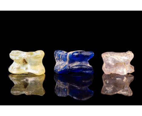 Ca. 300 - 100 BC.
A set of three glass astragali, each representing the form of a sheep or goat knucklebone. The name &ldquo;