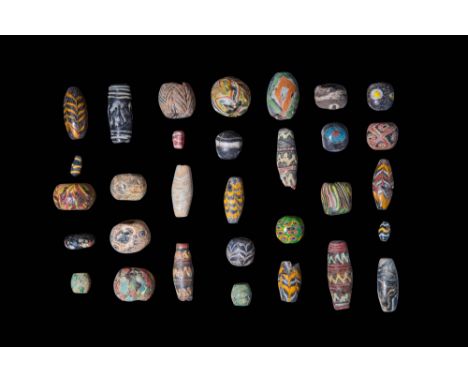 Ca. 600 - 400 BC.A collection of 31 glass mosaic beads displaying a diverse array of shapes, sizes, and decorative techniques