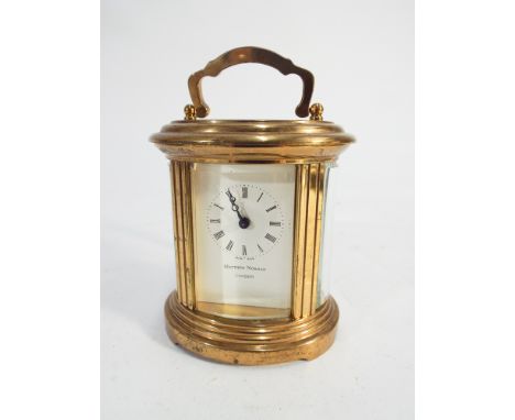 Miniature brass oval carriage clock by Mathew Norman of London.  Swiss made, 6.5cm high excluding handle.  With key 
