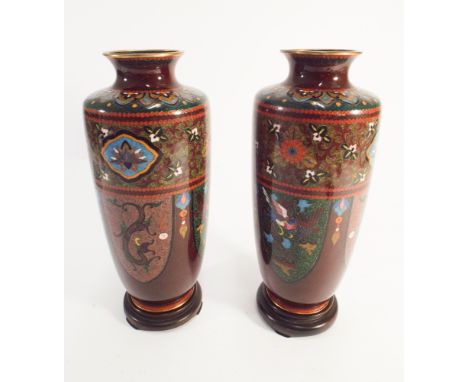 A pair of quality Japanese Cloisonne enamel vases with an iron red ground on circular hardwood vase stands. Vases stand appro