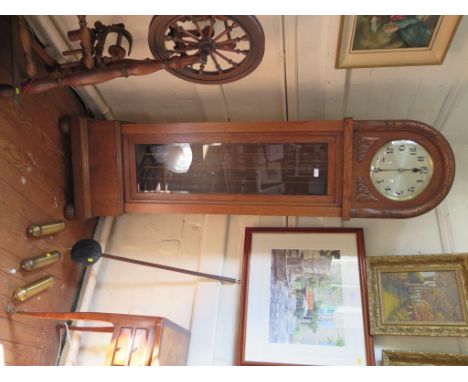 A 1930s oak longcase clock, the arched case enclosing a silvered dial above a glazed trunk and lobed feet, the three train mo