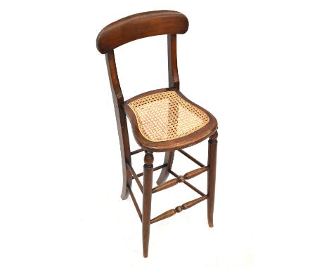 A Victorian child's correction chair with curved top rail, open back, lattice weave seat, on tall sabre legs with bobbin turn