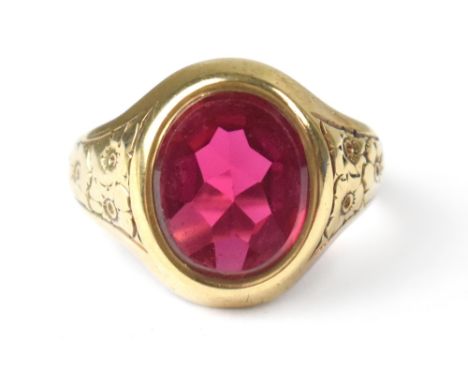 A vintage 9ct gold gentlemen's signet ring with oval cut ruby coloured stone in bezel setting and engraved floral pattern to 