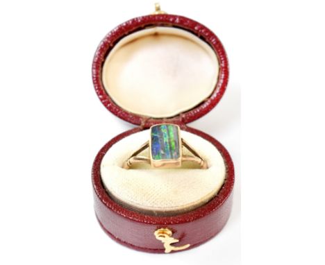 A vintage 9ct gold opal ring, the rectangular bezel set opal with lines of green, blue and black, mounted on split shoulders,