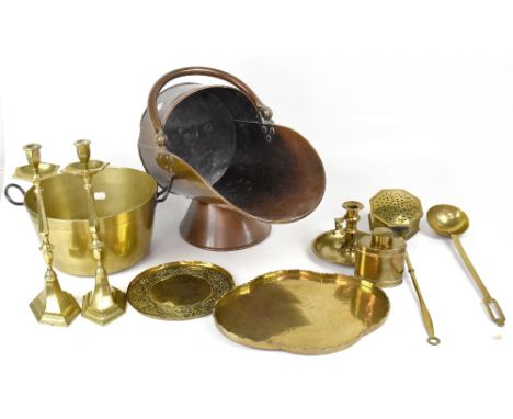 A quantity of brass and copper ware to include a copper coal scuttle, brass jam pan, trays, pair of candlesticks, chamber sti