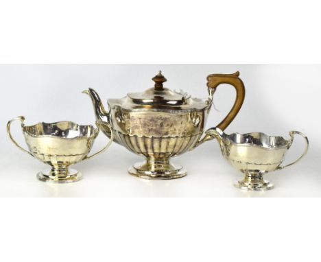 A George V hallmarked silver three-piece tea service comprising teapot with wooden handle and finial, sucrier and milk jug, O