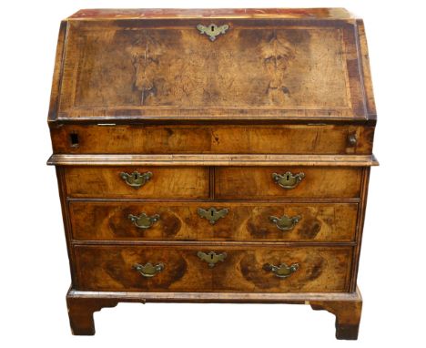 An early 18th century walnut bureau, with stepped fitted interior, 2 short and 2 long drawers below with brass drop handles a