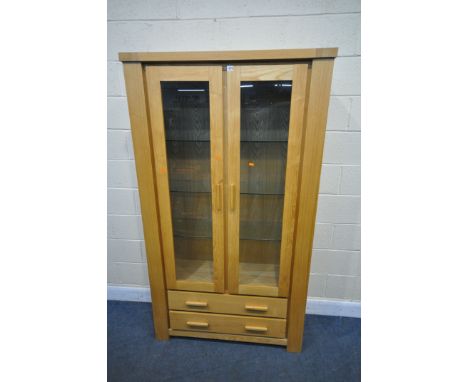 A MORRIS FURNITURE LIGHT OAK BOOKCASE, with two glazed doors, enclosing three glass shelves, above two long drawers, width 10