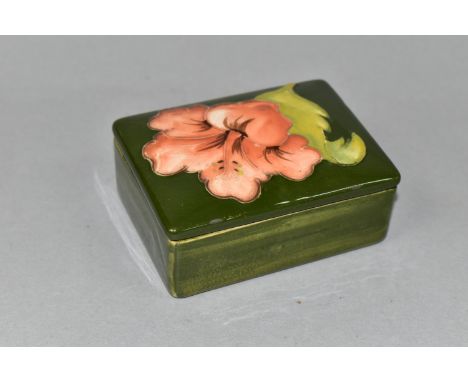 A MOORCROFT POTTERY RECTANGULAR TRINKET BOX AND COVER DECORATED IN A CORAL HIBISCUS PATTERN, on a green ground, blue printed 