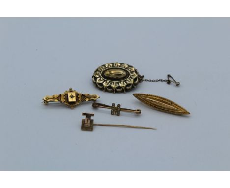 A collection of gold brooches, featuring two Victorian revival brooches in 9ct gold, a modernist 9ct gold stick pin, a 9ct go