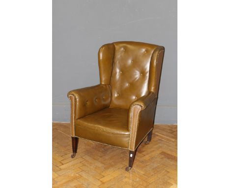 A late 19th century chocolate button hide upholstered drawing room armchair raised on square tapering forelegs and ceramic ca